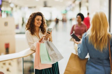 Alışveriş merkezinde alışveriş yaparken cep telefonu kullanan şık bir kadın..