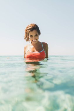 Genç ve güzel bir kadın denizde yıkanır. Gülümsüyor ve kameraya bakıyor..