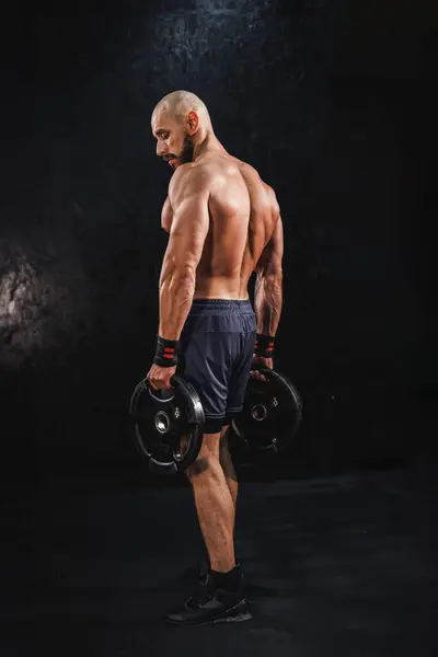 ジムで体重プレートでトレーニングを強化する準備をしている筋肉の若いフィットネス男性のショット — ストック写真