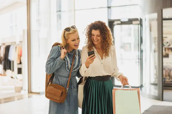Shot Two Cheerful Female Friends Surfing Smartphone While Walking Shopping — Stock Photo, Image