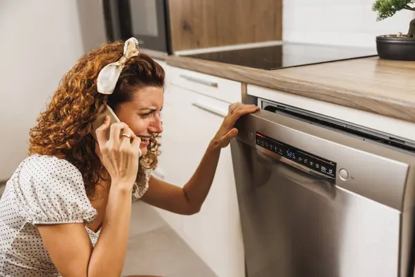 Беспокойная Женщина Зовет Помощь Телефону Пользуется Посудомоечной Машиной Кухне Стоковое Изображение