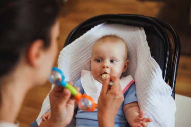 Tanımlanamayan bir kadının sandalyeye oturmuş bebeğini beslemesi..
