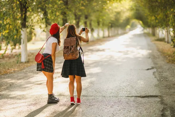 两个年轻快乐的女人走在大街上拍照时的后视镜 图库照片