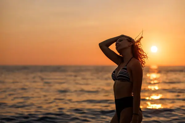 迷人的年轻女子正在热带海滩上摆姿势欣赏日落 图库照片