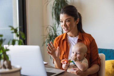 Anne kızına bakıcılık yaparken ve evde çalışırken video araması yapmakla meşgul..