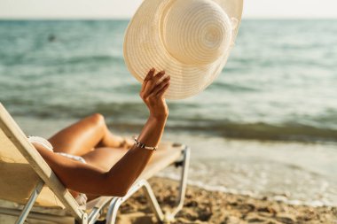 Bikinili çekici bir genç kadının sahilde tatilin tadını çıkartırken çekilen fotoğrafı..