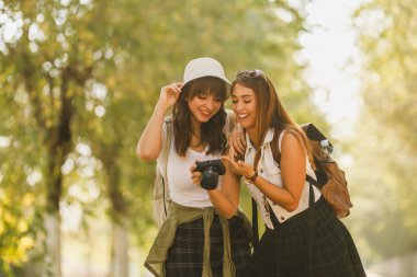 Sırt çantalı iki güzel genç kadın, saflık içinde yürürken kameradaki fotoğraflara bakıyor..