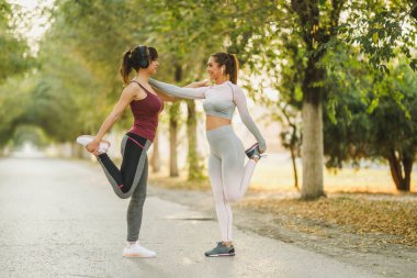Mutlu iki genç kadın cadde boyunca koşmadan önce alıştırma yapıyor..