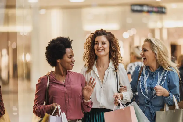 Stock image A group of cheerful multicultural women embracing retail therapy and fashion in a vibrant city mall.