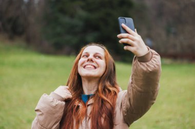 Telli gülümseyen genç bir kadın cep telefonu havada duruyor ve önemli bir simgeyi yakalıyor..
