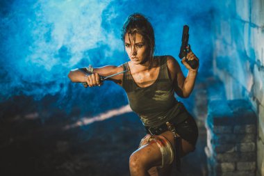 Terk edilmiş harabelerde saldırıya hazırlanırken elinde bıçak ve silah tutan çok güzel bir kadın..