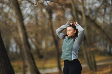Genç bayan dışarıda antrenman için hazırlanıyor ve saçını bağlıyor..
