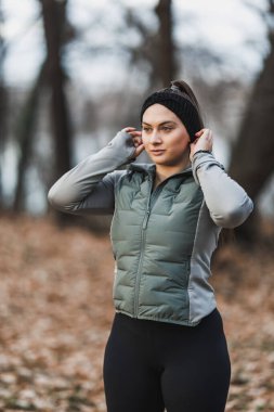 Serin bir sonbahar gününde açık hava koşusuna başlamadan önce saç bandı ve spor kıyafeti giyen odaklanmış genç bir kadın..