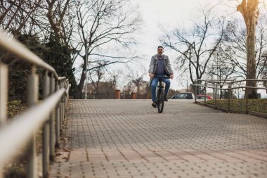 Bir adam şehir parkında bir tuğla yolda bisiklet sürüyor..