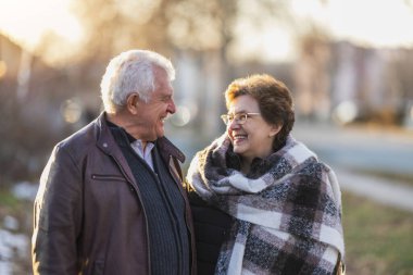 Gülümseyen yaşlı bir çift yan yana durmuş, rahatça sohbet ediyorlar..