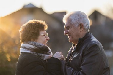 Mutlu bir son sınıf çifti portresi, el ele ve gülümsüyor, sonbahar emeklilik tatillerinde doğanın güzelliğinin tadını çıkarıyor..