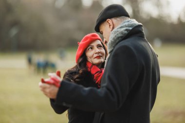 Orta yaşlı bir çift, bir sonbahar sezonunda parkta dans ederken bir anlık neşeye kapılır..