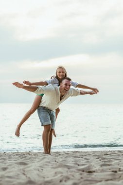 Bir baba, sahil kenarında sakin bir gezinti yapan bir kızı sırtında taşıyor..