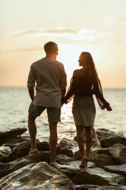 Sevgi dolu bir çift gün batımında boş kayalık kumsalda yürüyor ve birbirlerini izliyorlar.. 