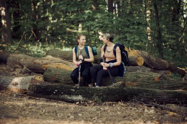 Mutlu genç kız ve annesi ormanda yürüyüşlerinin bir kısmında mola veriyorlar..