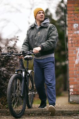 Orta yaşlı bir adam kaldırımda bisikletinin yanında yürüyordu..