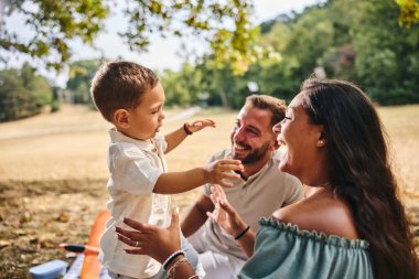 Neşeli mutlu aile doğada eğlenirken ebeveynler oğullarıyla oynuyorlar.. 