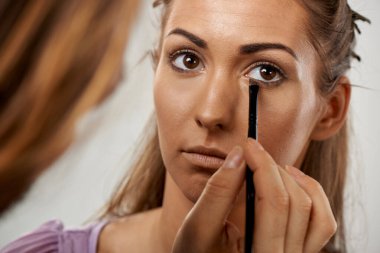 Bir kadın dikkatlice bir fırçayla göz farı sürüyor, gözüne odaklanıyor.. 