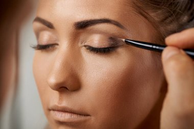  Makyaj sanatçısı yakın plan bir model üzerinde göz makyajı yapıyor.. 