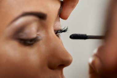 Profesyonel makyaj sanatçısının müşteriye rimel uygulaması..