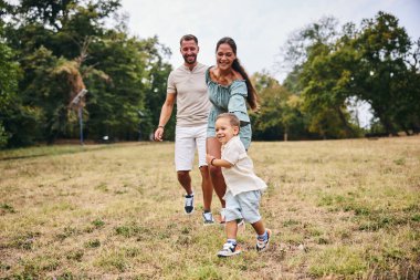 Güzel bir parkta koşan oğluyla mutlu bir aile.. 
