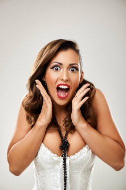 Bir kadın, elleri yüzündeyken şaşkınlık ve heyecan ifade eder..