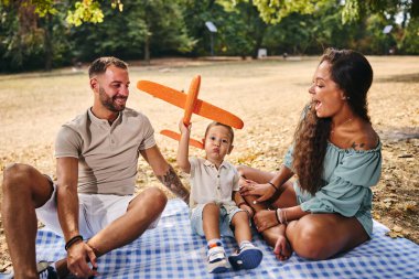 Çocuk doğada ailesiyle oyuncak bir uçakla oynuyor..