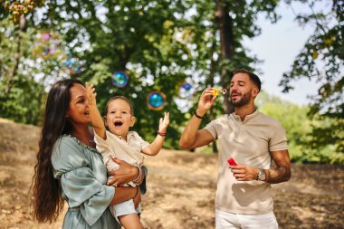 Mutlu ebeveynler, doğada kabarcıklarla oynayıp eğleniyorlar.. 