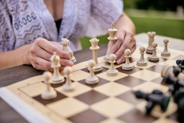 Satranç taşlarını açık hava tahtasına dikkatlice yerleştiren biri.. 