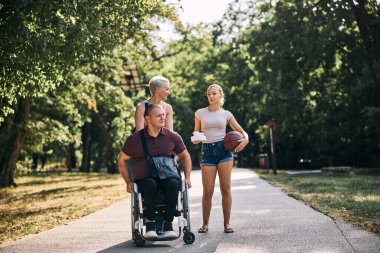 Mutlu bir aile, dışarıda tekerlekli sandalyedeki bir adamla güzel vakit geçirir.. 