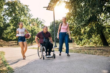Aile parkta güneşli bir gün geçiriyor. Babasıyla tekerlekli sandalyede.. 