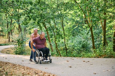 İnsanlar tekerlekli sandalyedeyken güzel parkta yürüyen bir çift.. 