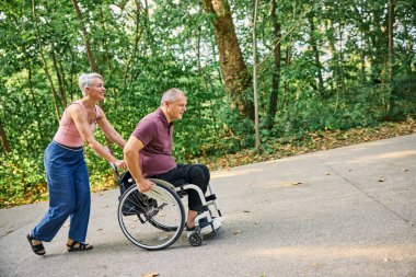 İnsanlar tekerlekli sandalyedeyken güzel parkta yürüyen bir çift.. 