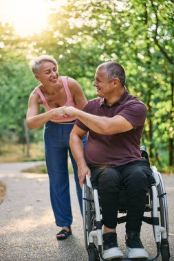 Adam tekerlekli sandalyedeyken parkta yürüyen mutlu çift.. 