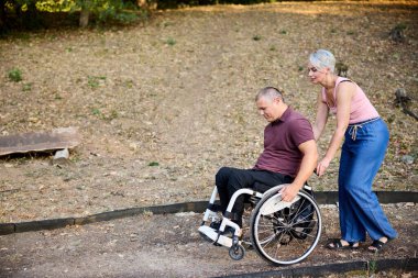 Bir çift, refakatçilik ve kapsayıcılığın altını çizerek, lüks bir parkta sakin bir şekilde yürümekten zevk alır..