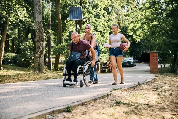 Mutlu bir aile, dışarıda tekerlekli sandalyedeki bir adamla güzel vakit geçirir.. 