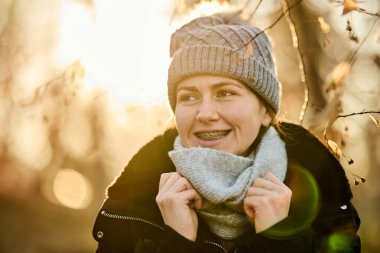 Sonbahar havasında parkta şapkası ve atkısı olan gülümseyen bir kadın.. 