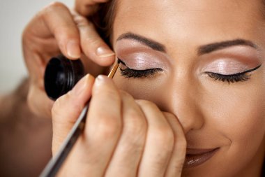 Yakın plan profesyonel makyaj sanatçısı göz kapağına değerli bir göz farı sürüyor.. 