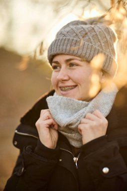 Sonbahar havasında parkta şapkası ve atkısı olan gülümseyen bir kadın.. 