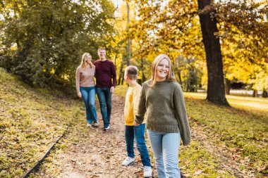 Dört kişilik neşeli bir aile güzel bir sonbahar parkında güzel bir yürüyüş yapıyor.. 