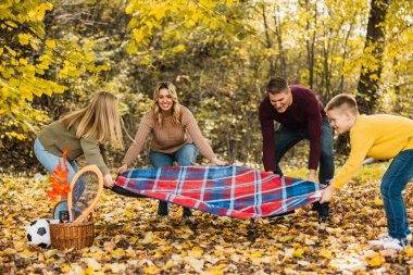 Dört kişilik aile güzel bir sonbahar gününde parkta piknik yapmaya hazırlanıyor.. 