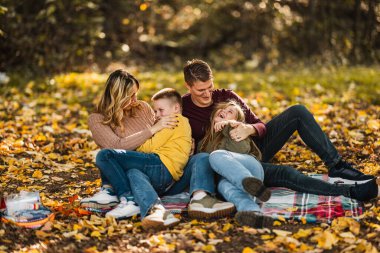 Dört kişilik mutlu bir aile güzel bir günde sonbahar parkında eğleniyor ve oyun oynuyor.. 