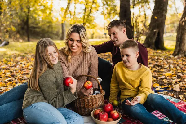 Mutlu, neşeli bir aile parkta piknik yapıyor ve sonbahar günü parkta elma yiyor.. 