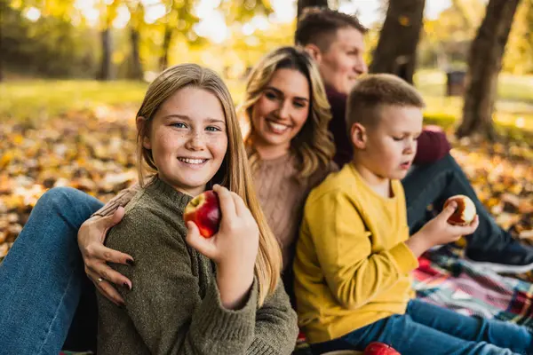 Mutlu bir aile parkta piknik yapar ve güzel bir sonbahar gününde parkta elma yer.. 