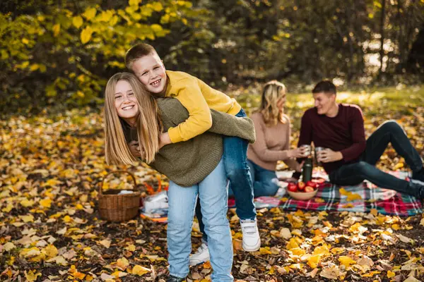 Erkek ve kız kardeş sonbahar günü parkta oynarken ebeveynler onları izliyor.. 